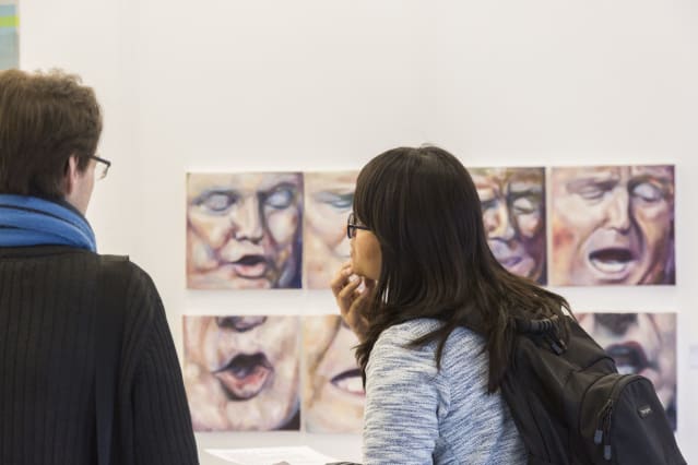 two people looking at the Shortlist art display at Tate exchange; the works they are paaign feature images of Donald Trump