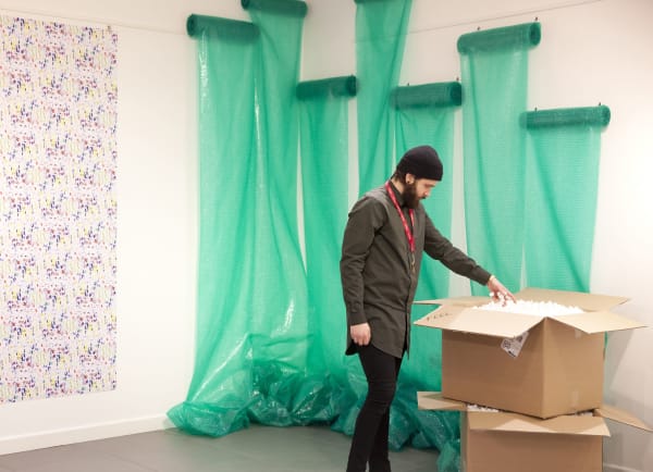 A visitor interacts with an element of the work, a box filled with polystyrene