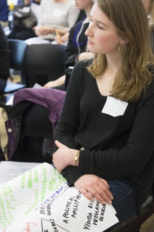 woman in a black top sits with a large sheet of notes from group discussions at Shape