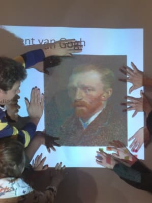 The young people framing a Vincent Van Gogh image with their hands.