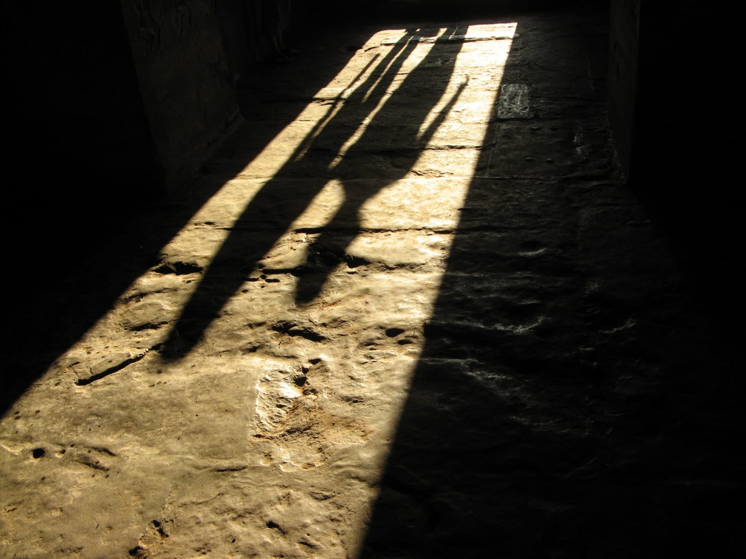 Photo of shadows cast by two people across a large stoney floor. 