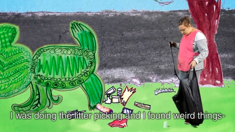 Wendy stands to the right of this landscape image wearing a pink apron and holds a black bin bag. She is immersed in a hand drawn park scene where she picks up rubbish left on the grass infant of her. There are captions at the bottom of the screen th