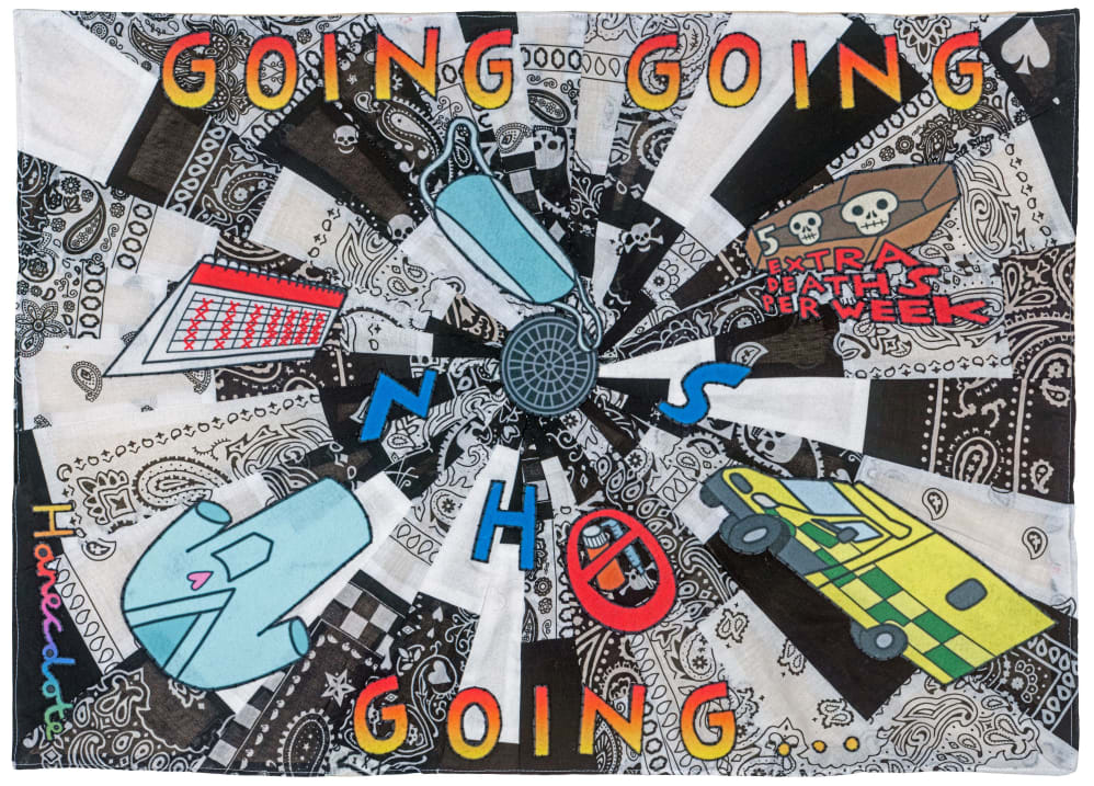 A landscape photo of a patchwork quilt in black and white patterned fabric, with embroidered objects familiar to the NHS overlaid on top. In orange-yellow text, the words ‘Going going going’ are arranged top and bottom.