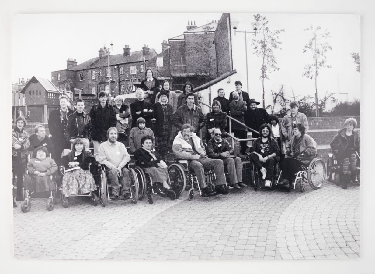 A black and white photograph of a group of people from the disability arts movement, some of whom are wheelchair users.